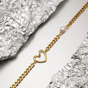 Detail of 18K gold paperclip necklace featuring a heart pendant and a white freshwater pearl
