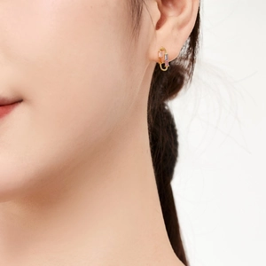 Close-up of gold paperclip earrings with pink, purple and amber rectangular crystals