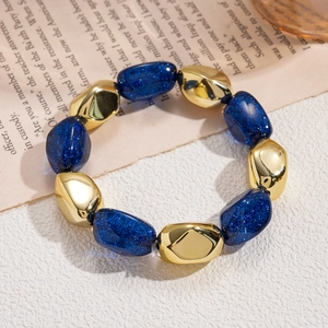 Detail of dark blue glitter resin beads and irregular gold-tone beads on a vintage book