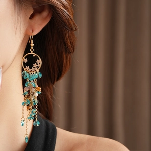 Macro detail of vintage gold fringe earrings with star design and blue crystal beads