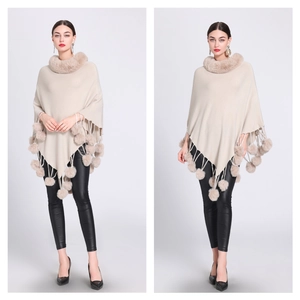 Chic beige knitted poncho featuring a faux rabbit fur collar and playful pom-pom tassels