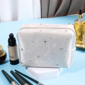 Star pattern velvet cosmetic bag in beige with gold embroidery on display stand