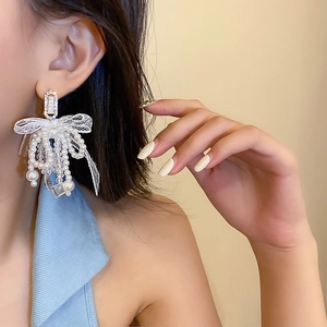 Boucles d'oreilles nœud en dentelle vintage avec perles et zircone portées par un mannequin
