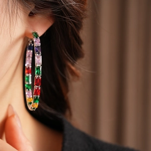 Close-up of oversized hoop earrings with multi-colored rectangular baguette zircons