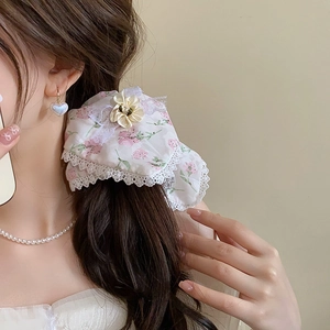 Vue détaillée du chouchou floral avec bordure en dentelle et fleur en satin sur modèle