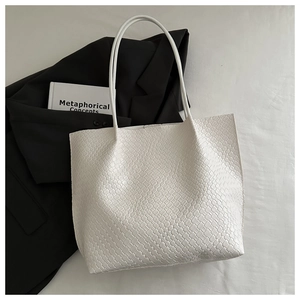 Close-up of woven texture on a white leather tote bag featuring modern minimalist style
