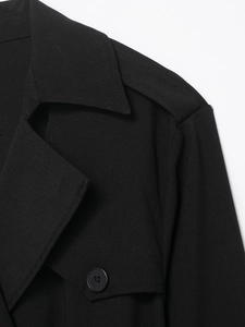 Detailed view of black trench-style midi dress lapel with premium woven texture