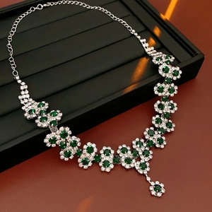 Close-up of sparkling sunflower pendant necklace with green gemstones on black display