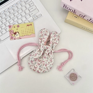 Floral fabric storage bag with rabbit ears shown on a stylish lifestyle desktop