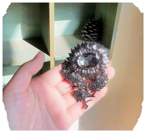 Detailed view of sunflower brooch with large crystal and gunmetal grey petals held in hand