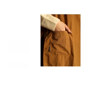 Detail of caramel apron pocket with Certainly embroidery and fabric texture focus