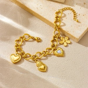 Vintage gold chunky chain bracelet with pearl heart and floral charms on stone surface