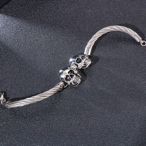 Macro de têtes de mort en argent et texture de câble en acier tressé sur le bracelet