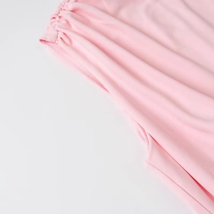 Détail du tissu de robe rose montrant la texture fine et les coutures plissées