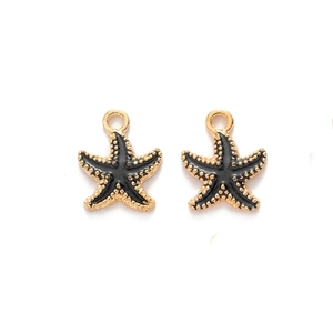 Macro shot of two black and gold starfish charms with enamel finish on white background