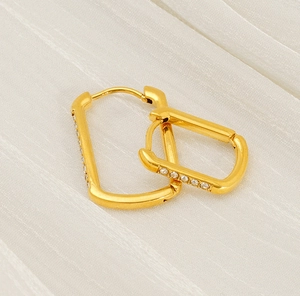Detail of gold U-shaped hoop earrings with sparkling cubic zirconia on white satin