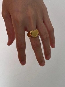Close-up of a stylish gold heart chain ring worn on a finger with metallic luster