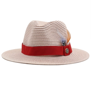 Classic beige straw fedora sun hat with red ribbon and decorative feathers on white background