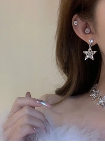 Détail du collier étoile argenté et des boucles d'oreilles sertis de pierres brillantes
