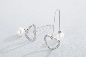 Detail of silver clover earrings with sparkling rhinestones and white pearls on top