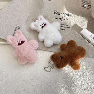 Close-up of cute plush bear charms in pink, white, and brown with metallic chains