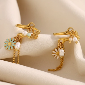 Detailed macro view of 18K gold-plated bee and daisy earrings with pearls on silk