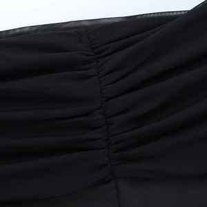 Macro view of black mesh fabric showing detailed ruching and fine texture of the dress