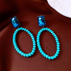 Macro detail of vintage silver needle oval earrings with deep blue gems and turquoise beads
