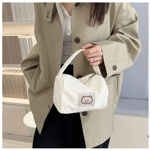 Detail of white corduroy mini handbag featuring a cute bear patch and metal zipper