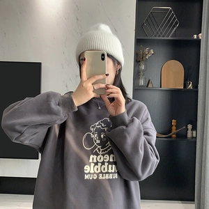 Detail of a white cable knit beanie hat styled with a dark grey cartoon sweatshirt