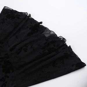 Détail de mini robe noire transparente avec motifs floraux floqués et bords à volants