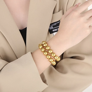 Polished gold beaded stretch bracelet set worn on wrist with chic layered design