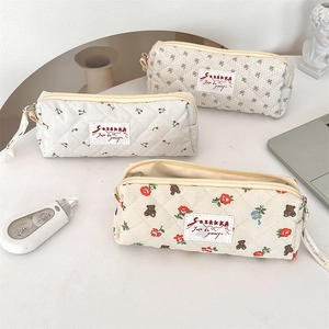 Vue détaillée de trois trousses matelassées aux motifs de fleurs et d'oursons sur bureau