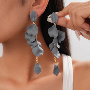 Close-up of matte grey acrylic petal tassel earrings worn by a model against white