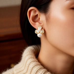 Close-up of elegant flower pearl earrings with zircons worn by a model in soft light