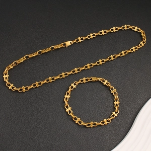 Detailed view of golden link chain necklace and bracelet set on black textured background