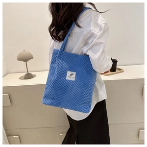 Detailed close-up of blue corduroy tote bag with 'You need this one' embroidery patch