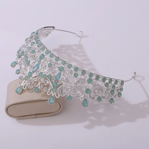 Detailed view of silver crown with light green gems and rhinestones on a display box