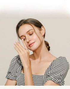 Detail of a thin 925 silver opal ring on a model wearing a plaid dress