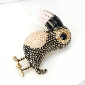Close-up of bird brooch with golden dots, black gemstone eye and enamel texture