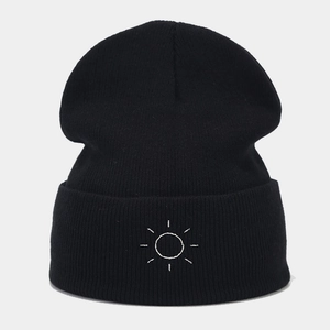 Close-up of sun embroidery detail on a black cuffed knit beanie hat for winter