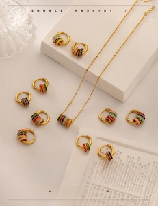 Macro view of vintage matte gold jewelry set featuring colorful enamel hoop earrings