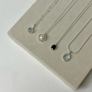 Elegant silver necklaces with heart pearl and gemstone pendants on a gray velvet mat