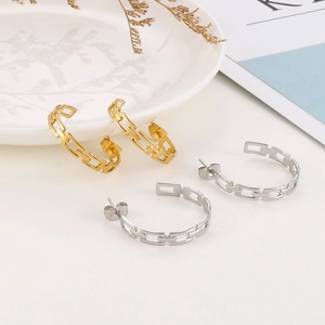 Detail view of gold and silver chain link C-hoop earrings on a minimalist white backdrop