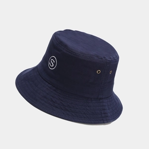 Close-up of navy cotton bucket hat with white 'S' embroidery and side metal eyelets
