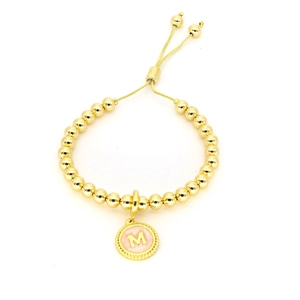 Détail du bracelet à billes dorées avec cordon ajustable et breloque lettre M émail rose
