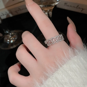 Close-up of silver hollowed crisscross ring with zircons worn on a finger in elegant lighting