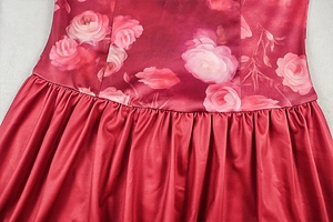 Dettaglio di un abito rosso a fiori che mostra le pieghe in vita e il tessuto satinato