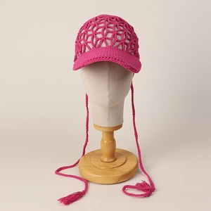 Detail of fuchsia handmade crochet hollow baseball cap with tassels on display stand