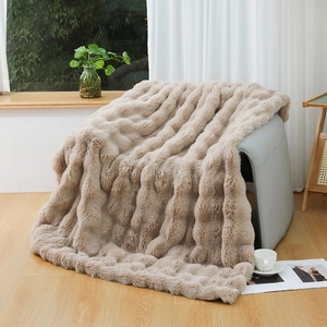 Detailed texture of thick beige faux rabbit fur blanket with wavy embossed patterns